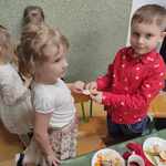 3.	Chłopiec w czerwonej koszuli i dziewczynka w białej bluzce dzielą się opłatkiem przy wigilijnym  stole. 