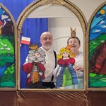Aktorzy trzymają kukiełki królowej i króla. Dookoła znajduje się bajkowa dekoracja.