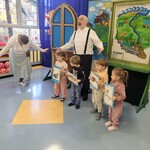 Aktorzy stoją wraz z dziećmi obok tablicy z mapą Polski. Dzieci trzymają zdjęcia zwierząt.