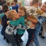Na zdjęciu dzieci uśmiechają się i przytulają.