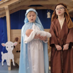 Dziewczynka przebrana za Maryję, chłopiec przebrany za Józefa, w tle drewniana stajenka.