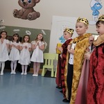 Chłopcy przebrani za trzech Króli, trzymają dary, obok stoją dziewczynki w strojach aniołków.