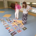 Dwie nauczycielki oglądają zdjęcia konkursowe, które leżą rozłożone na podłodze.