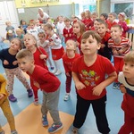 Zdjęcie przedstawia dużą grupę kolorowo ubranych dzieci , które tańczą.